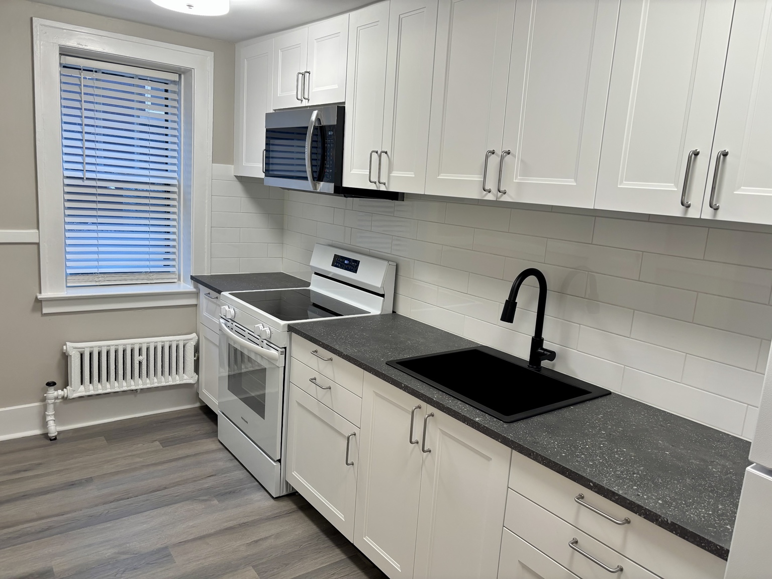 Kitchen with white cabinets, stove, microwave and black sink — 430 Giles Blvd W., Windsor, Ontario